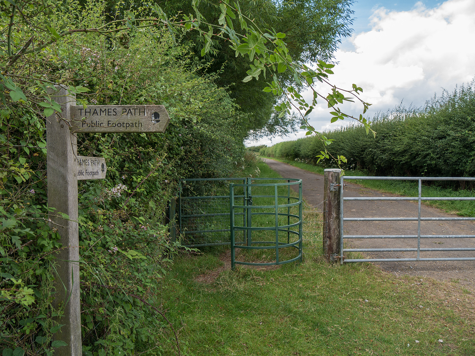After a series of fields (to the right in this picture) the path reaches a tarmac road via a kissing gate